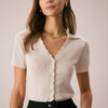 La camiseta de punto con cuello en V y botones en color nude
